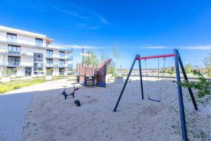 an empty playground withswing equipment in front of a building at Apartament Classic Spa&Wellness by Major Domus Club in Dziwnów