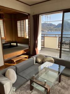 un soggiorno con divano e tavolo in vetro di Kitaizu North Private House - Vacation STAY 14216 a Numazu