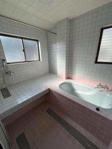 een roze badkamer met een bad en een wastafel bij Kitaizu North Private House - Vacation STAY 14216 in Numazu