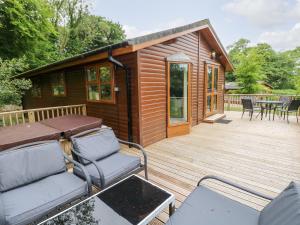 a small cabin with a deck with a table and chairs at The Beeches in Narberth
