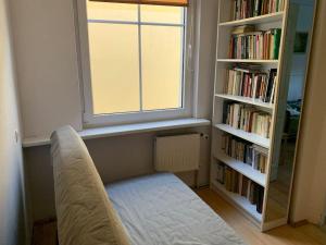 a room with a window and a bench in front of a book shelf at Sopot Green 65 in Sopot