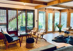 a living room with chairs and tables and windows at Whitewater Byron Bay in Byron Bay