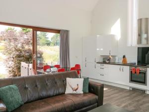 a living room with a brown couch and a kitchen at Casterbridge in Broadwey