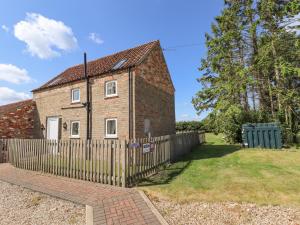 a brick house with a fence in front of it at Holly Cottage in Alford