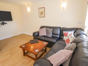 a living room with a leather couch and a table at Holly Cottage in Alford