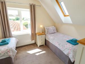 a bedroom with two beds and a window at Holly Cottage in Alford