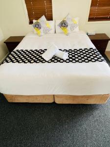 a large bed with a black and white blanket on it at Jacaranda Place Motor Inn in Toowoomba