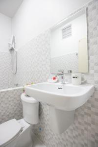 a white bathroom with a sink and a toilet at Tonsoi Hathairat in Ban Tao Pun