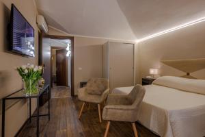 a hotel room with a bed and two chairs at Albergo Alassio in Montecatini Terme