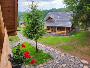 a house with a tree and flowers in front of it at Harghita Log Houses in Izvoare