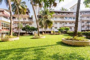 un gran edificio con palmeras en un parque en 'Serene Escape' Top Floor 1BHK Apartment with AC, Wi-Fi, Gym & Pool, 5-Minute Walk to the Beach, and Captivating Tree and Garden Views, en Colva