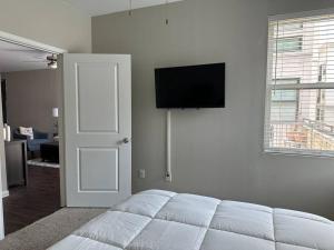 1 dormitorio con 1 cama blanca y TV de pantalla plana en Trendy, upscale apartment!, en Houston
