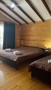 two beds in a room with wooden walls at MiMi in Tsandrypsh