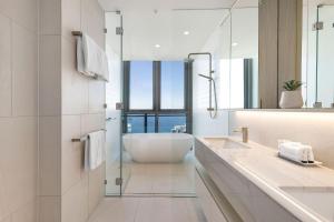 a white bathroom with a tub and a sink at ULTIQA Signature at Broadbeach in Gold Coast