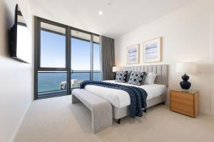 a white bedroom with a bed and a large window at ULTIQA Signature at Broadbeach in Gold Coast
