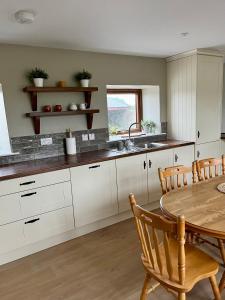 a kitchen with white cabinets and a wooden table at Tom Rocky’s Farmyard in Templemore