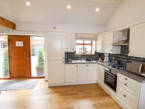 a kitchen with white cabinets and a wooden floor at The Stables in Preston