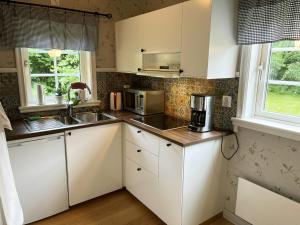 uma cozinha com armários brancos e um lavatório em Newly built cozy cottage on the east side of Öland em Färjestaden
