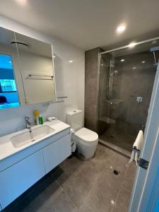 Un baño con inodoro, lavabo y ducha. en Cozy 3BR Apartment Walking Distance to GOMA, en Brisbane