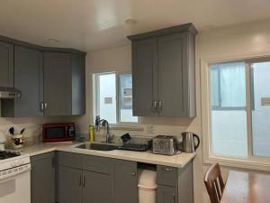 a kitchen with gray cabinets and a sink and a microwave at Affordable Private Rooms with Shared Bath Kitchen near SFO (SA) in Daly City