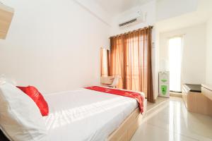 een slaapkamer met een wit bed en een raam bij RedLiving Apartemen Sayana - Premium Property in Tambun-lobangbuaja