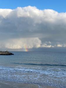 a rainbow in the sky over the ocean with a beach at Waves of the Sea in Mangalia