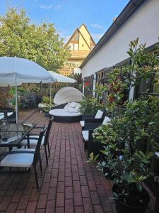 eine Terrasse mit Stühlen, Tischen und Sonnenschirmen in der Unterkunft Gästehaus Engelgasse Herzogenaurach in Herzogenaurach