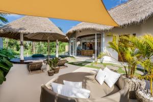 een patio met een bank en parasols bij Villa Kizmet Fit by BaliSuperHost in Ubud