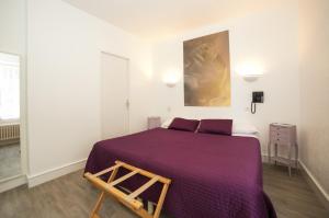 a bedroom with a large bed with a purple blanket at Hôtel An Ti Gwenn in Carnac