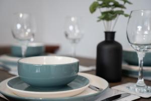 a table with a blue bowl and plates and a vase at Linburn Apartment in Glasgow