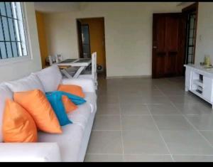 ein Wohnzimmer mit einer weißen Couch mit orangefarbenen und blauen Kissen in der Unterkunft Apartamento a 5 minutos Zona Colonial in Santo Domingo