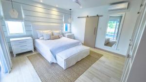 a bedroom with a white bed and a mirror at Unforgettable 3BR Luxury Villa at Porter's Place in Saint James