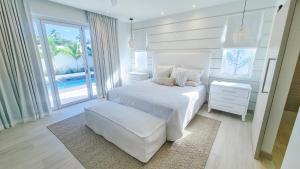 a white bedroom with a white bed and a chair at Unforgettable 3BR Luxury Villa at Porter's Place in Saint James