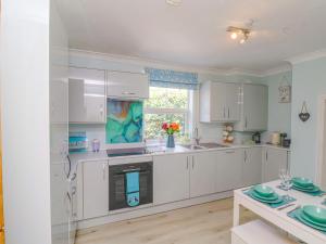 a large kitchen with white cabinets and a window at 2 Cobb View in Lyme Regis