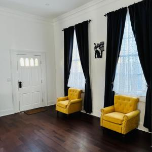 two yellow chairs in a living room with black curtains at Endless Story Magazine Suite Walk French Quarter in New Orleans