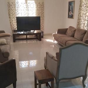sala de estar con sofá y TV en Baran Homestay, en Mascate
