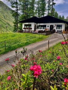 a white house with a black roof and some flowers at Apartment Gletscherbergblick in Obergurgl