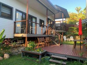 a house with a deck with chairs and a table at Coffs Harbour Sanctuary in Coffs Harbour