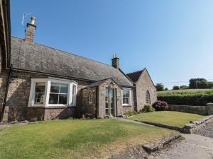 una antigua casa de ladrillo con un gran patio en The Coach House, en Cornhill-on-tweed