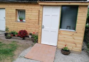 a wooden shed with a white door and some plants at Jono Trobele in Druskininkai