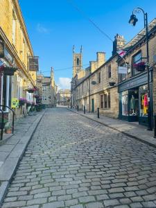 a cobblestone street in an old town with a church at Cobbles Cottage, Honley in Honley