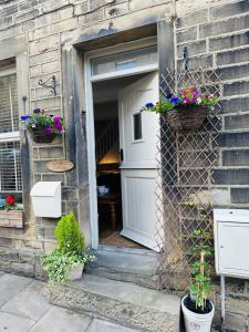 uma porta da frente de uma casa com cestos de flores em Cobbles Cottage, Honley em Honley