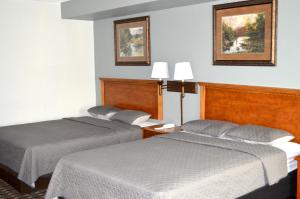 a hotel room with two beds and two pictures on the wall at Americas Best Value Inn and Suites St. Cloud in Saint Cloud