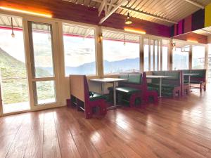 uma sala de jantar com mesas, cadeiras e janelas em Hotel Kempty - A Boutique Hotel, Mussoorie em Mussoorie