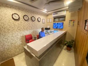 a man sitting at a counter in a room with clocks at Hotel Jodiya - Near CST in Mumbai