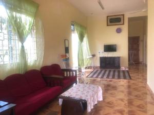 uma sala de estar com um sofá vermelho e uma televisão em Homestay Seri Hampar, Pendang em Pendang