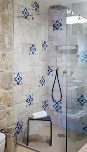 y baño con ducha y azulejos azules y blancos. en Masseria Della Volpe en Casale Modica