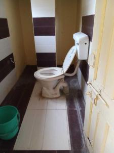 a bathroom with a toilet and a green bucket at SPOT ON Hotel Ellora in Raipur