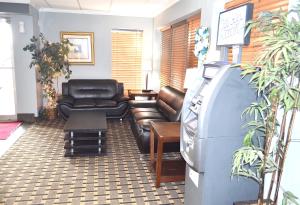 a waiting room with a leather couch and a tv at Americas Best Value Inn and Suites St. Cloud in Saint Cloud