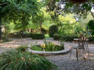 un jardín con un banco y una fuente en un parque en Maison du Loup, en Ganges